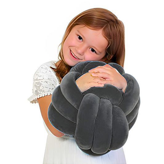 Child holding a gray neck pillow against a white background