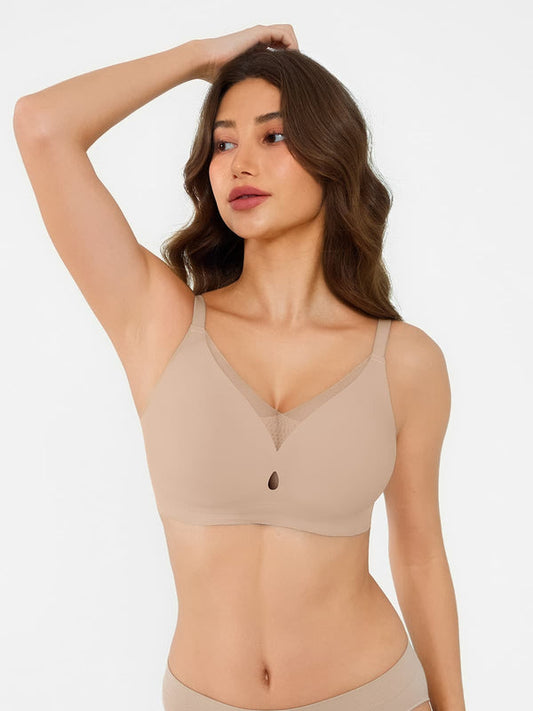 A woman modeling a beige wireless bra with a V-neckline and subtle mesh panel detail, shown against a plain light background.