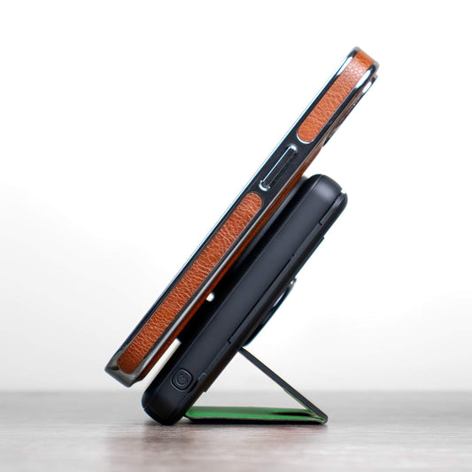 A black NYTSTND Pulse Power Bank with a green accent on the magnetic charging surface, standing upright with an adjustable kickstand.