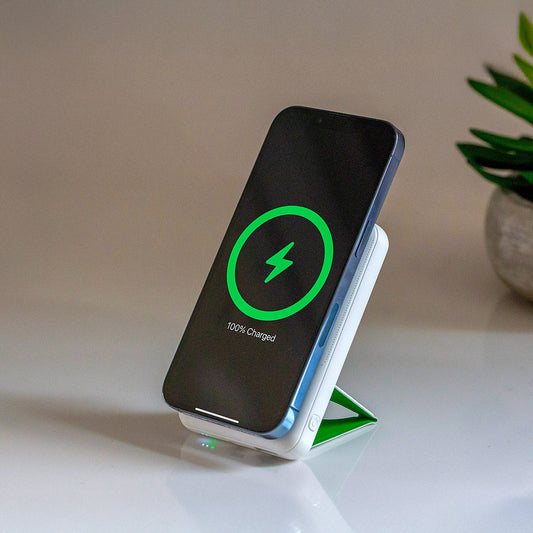 A white NYTSTND Pulse Power Bank with a green circle indicating the magnetic charging area, featuring an adjustable kickstand.