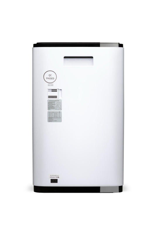 Air purifier on a gray floor with a yellow chair and wooden shelf in the background