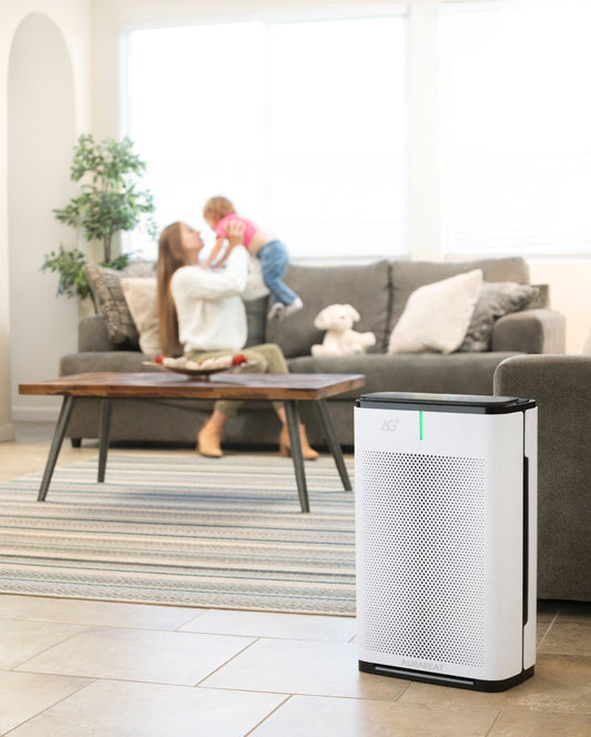 Air purifier on a gray floor with a yellow chair and wooden shelf in the background