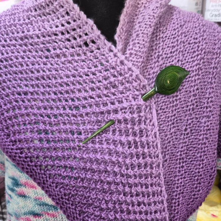 Close-up of a purple knitted garment with green buttons on a blurred background