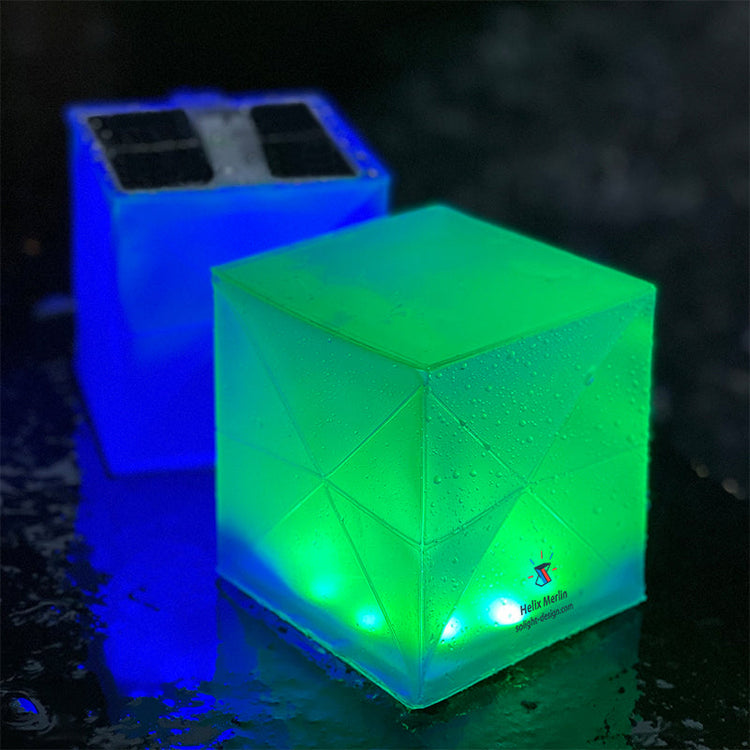 Two glowing cubes, one green and one blue, on a dark surface.