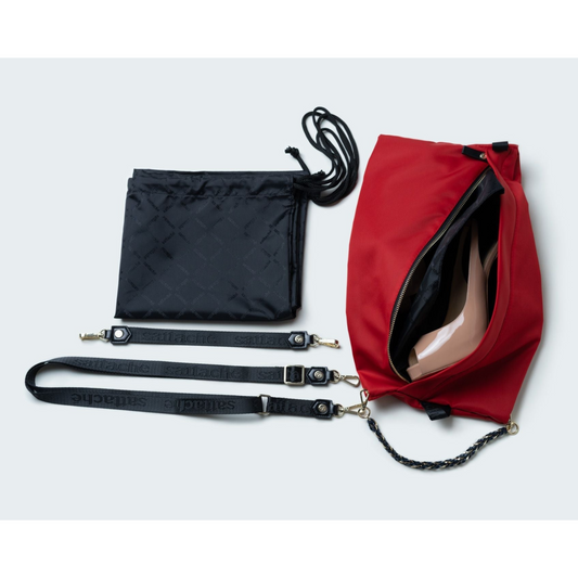 Red bag with black straps and chain detail on a light gray background