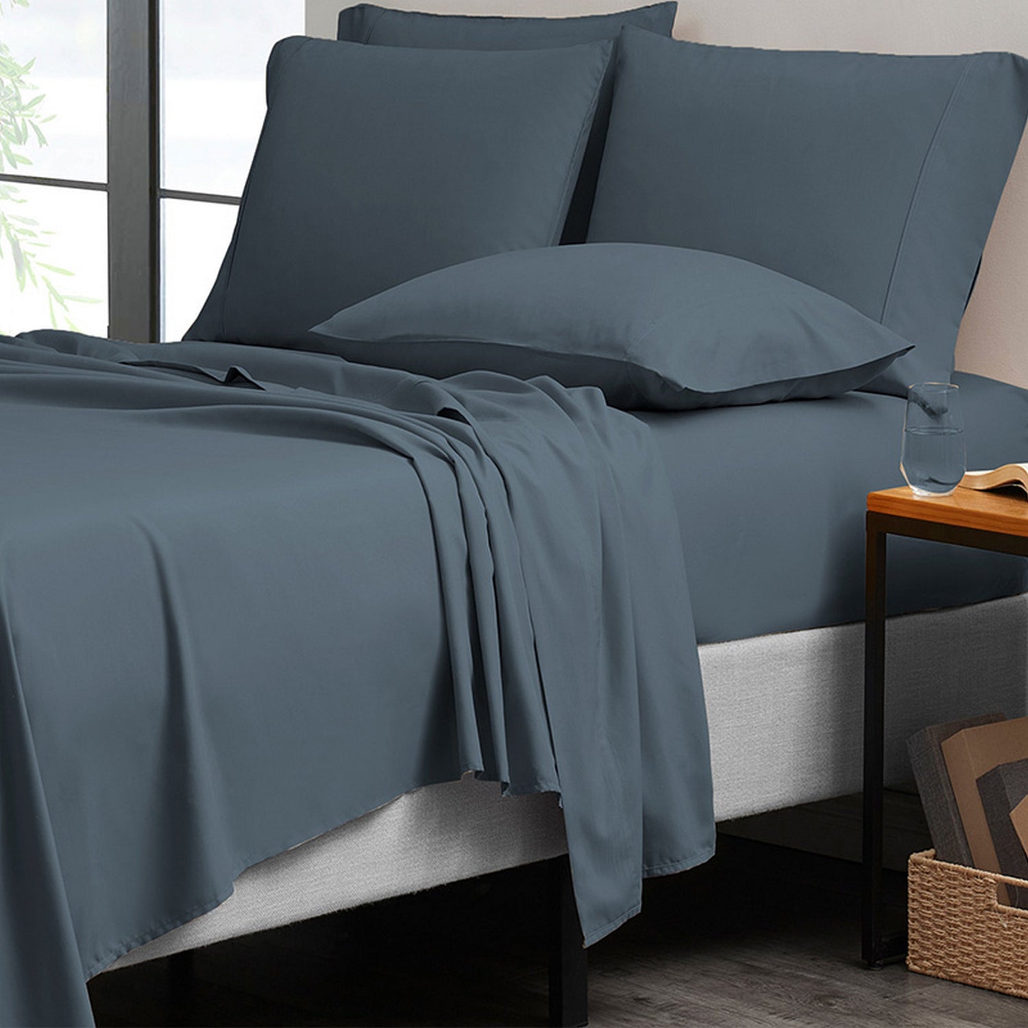 Blue bedding set on a bed with pillows and a side table.