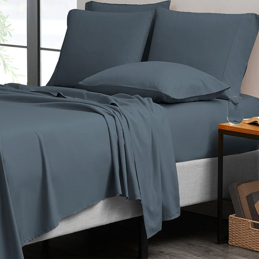 Blue bedding set on a bed with pillows and a side table.