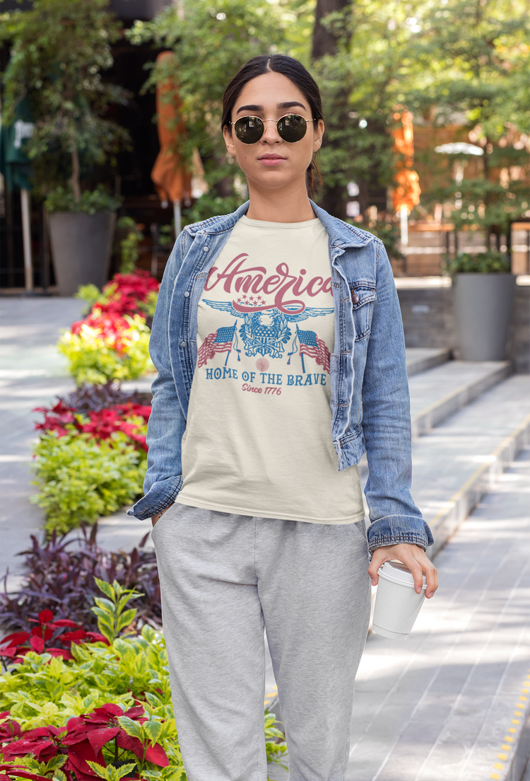Person wearing a t-shirt with 'America Home of the Brave' design outdoors.