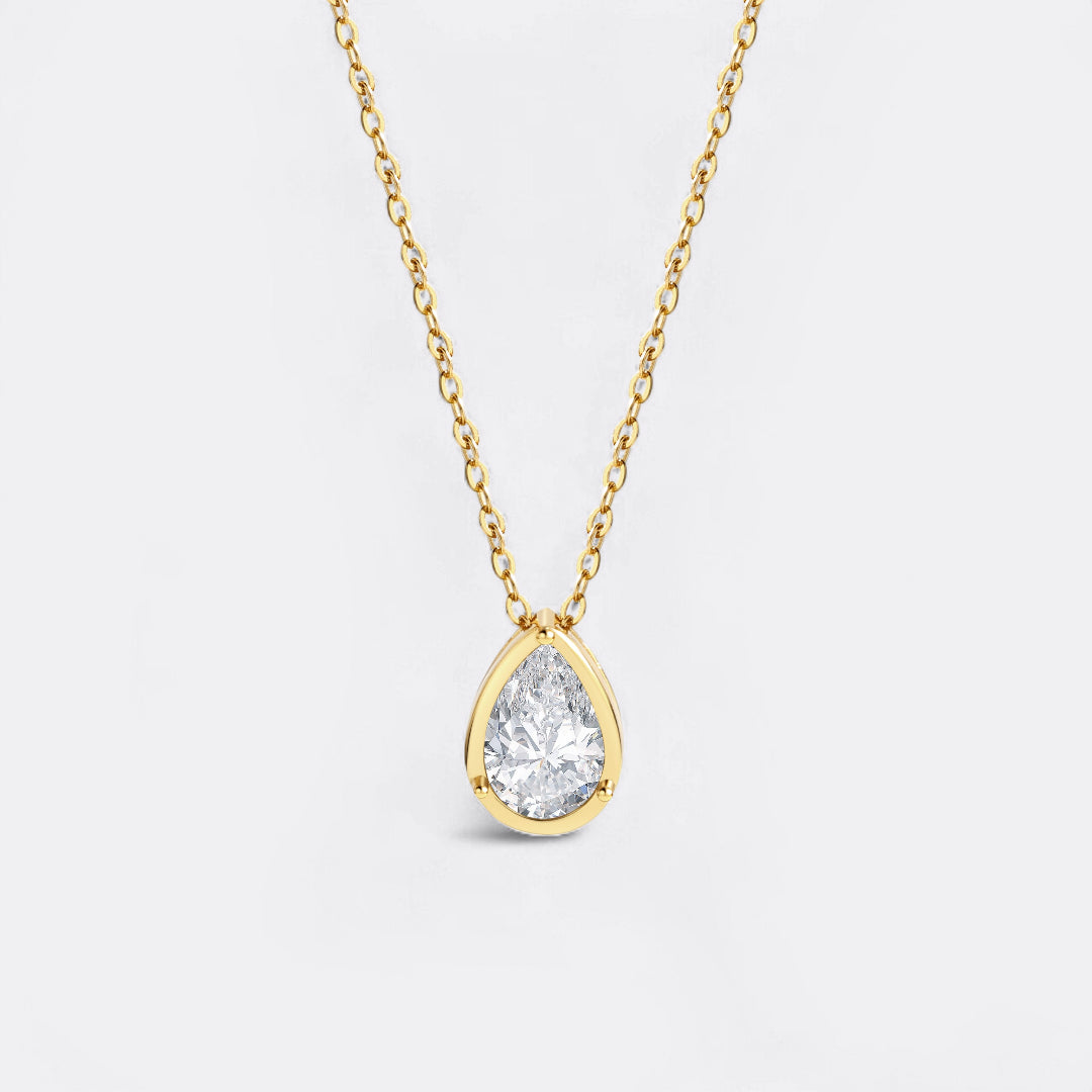Gold necklace with a teardrop-shaped diamond pendant on a light gray background