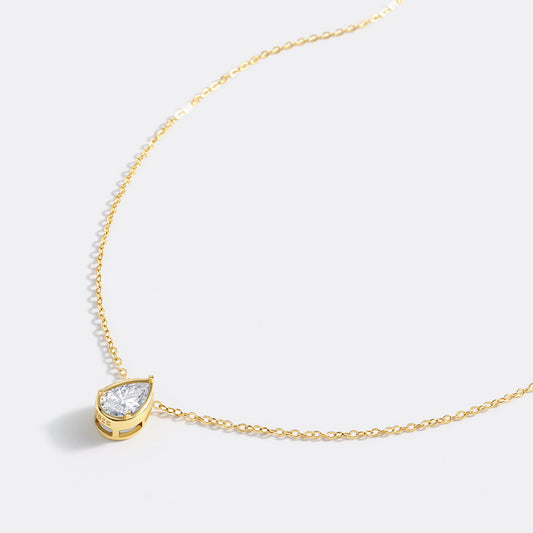 Gold necklace with a teardrop-shaped diamond pendant on a white background