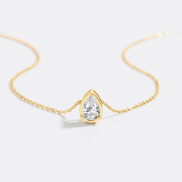 Gold necklace with a teardrop-shaped diamond pendant on a white background