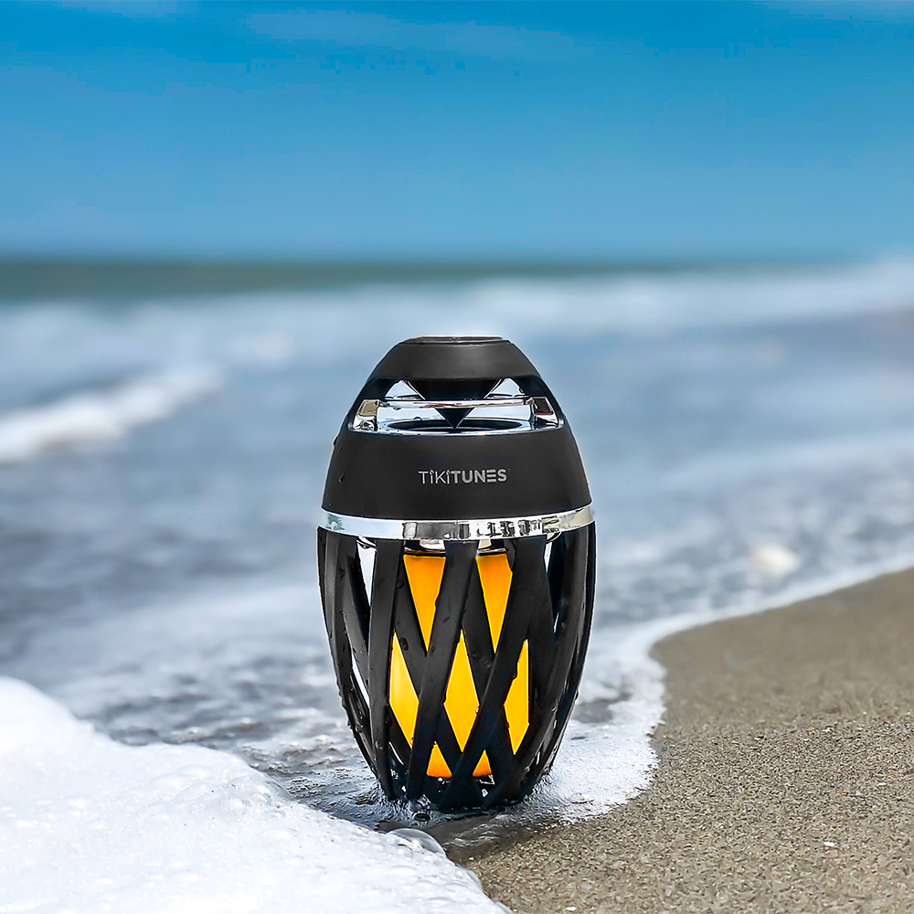 Tikitunes speaker on a beach with ocean waves in the background