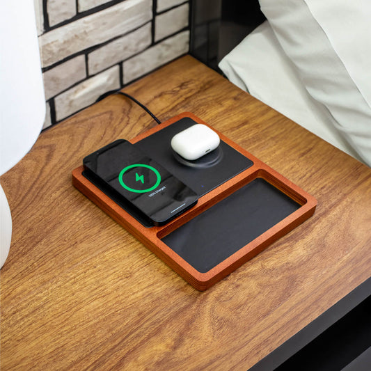 A black and oak wood 2-in-1 MagSafe wireless charging pad with a smartphone and earbuds being charged on it.