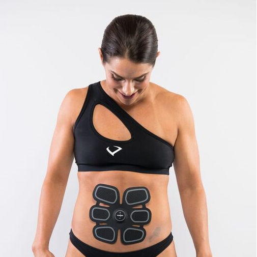Woman wearing a black sports bra and electronic abdominal muscle stimulator on a white background