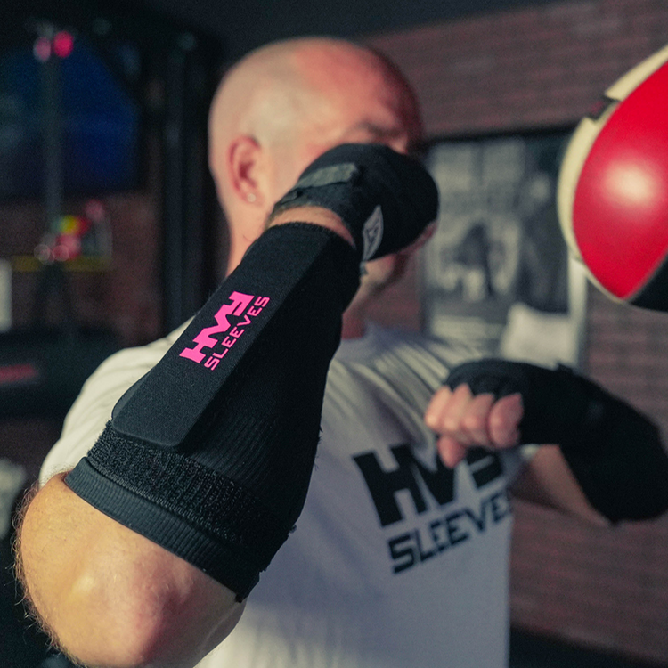 Person wearing black HVF sleeves with pink logo, blurred background