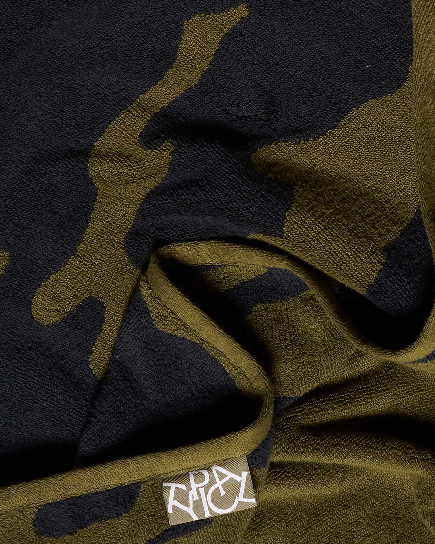 Camouflage-patterned fabric with a brand label on a dark background