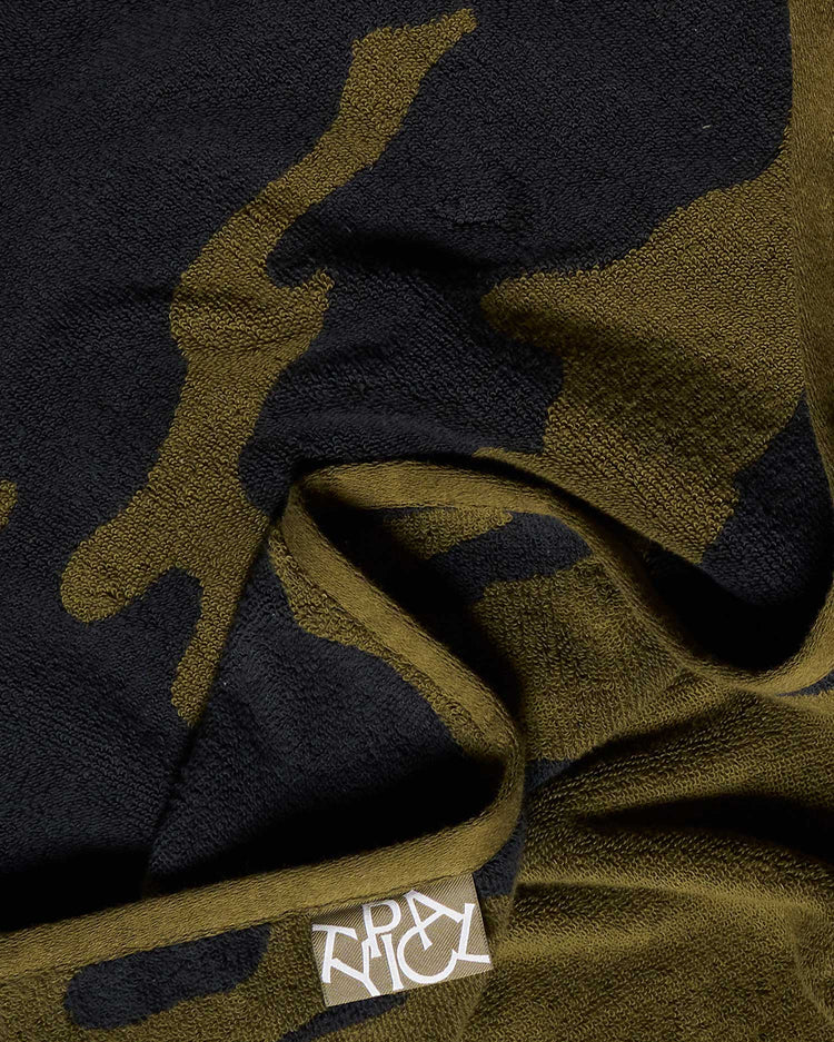 Camouflage-patterned fabric with a brand label on a dark background