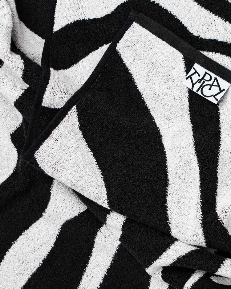Black and white striped towel with a brand label on a textured background