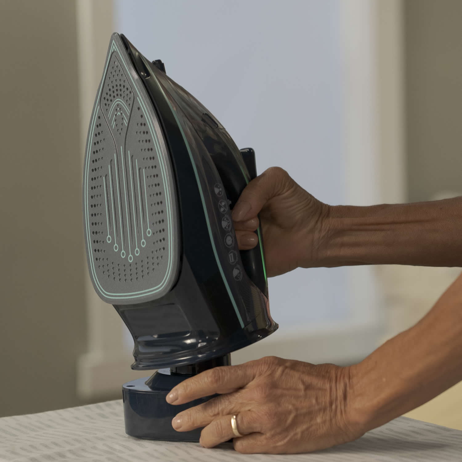 Person using a black iron on a light-colored fabric