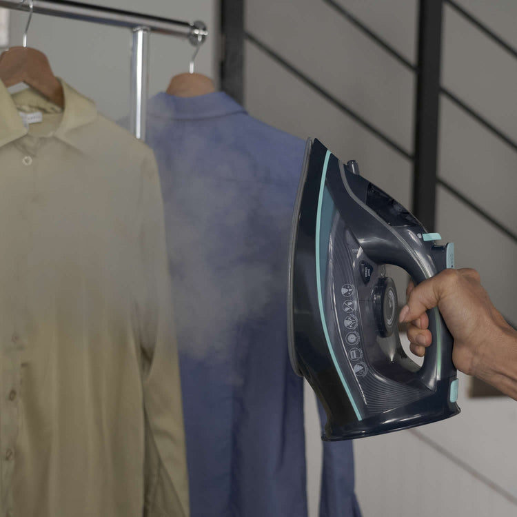 Person using a steam iron on a shirt with a blurred background