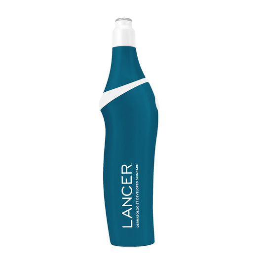 A person is using a pink microdermabrasion device on their leg in a bathroom setting.